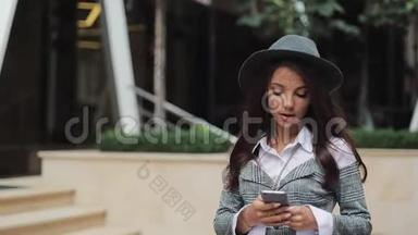 专业的年轻女商人用智能手机在<strong>城市街道</strong>上<strong>行走</strong>。 概念：新业务、交流、银行家
